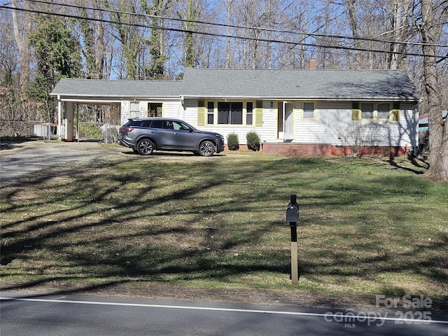 single story home with a front lawn, a carport, and roof with shingles