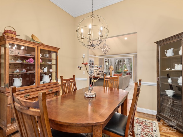 dining space featuring crown molding, light wood-type flooring, a notable chandelier, and baseboards