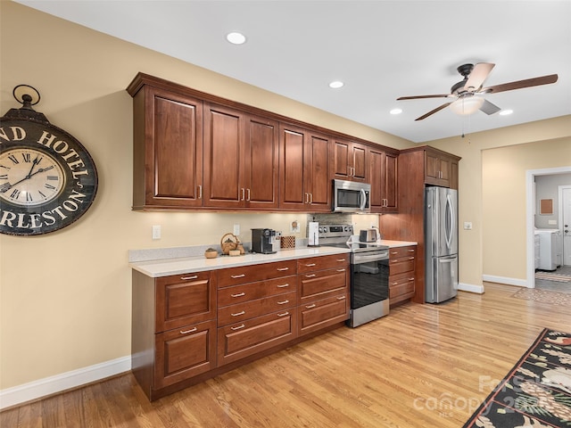 kitchen featuring stainless steel appliances, baseboards, light countertops, light wood finished floors, and washer and clothes dryer