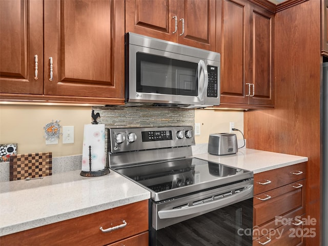 kitchen featuring appliances with stainless steel finishes, light stone countertops, brown cabinetry, and tasteful backsplash