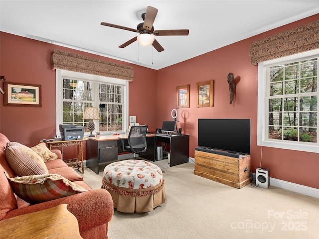 carpeted office space with ceiling fan and baseboards