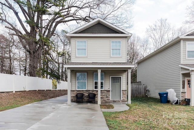 view of front of property with covered porch, stone siding, fence, and a front lawn