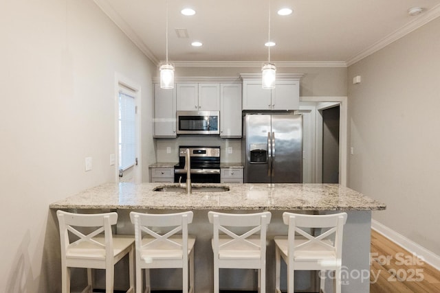 kitchen featuring stainless steel appliances, light wood-style floors, a breakfast bar, and crown molding