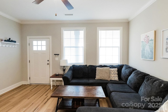 living area featuring light wood-style floors, visible vents, ornamental molding, and baseboards