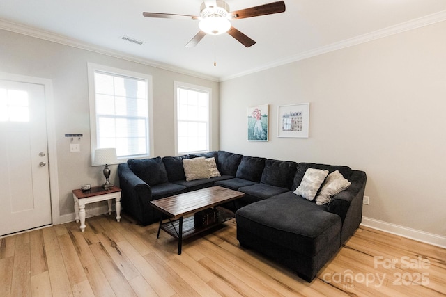 living area featuring light wood finished floors, baseboards, visible vents, ceiling fan, and crown molding