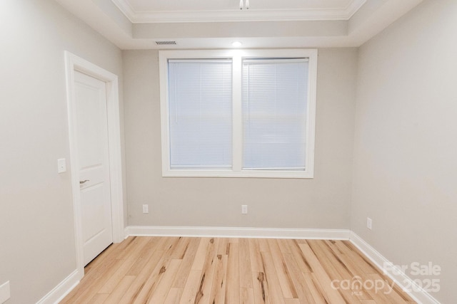 unfurnished room with light wood-style floors, visible vents, ornamental molding, and baseboards