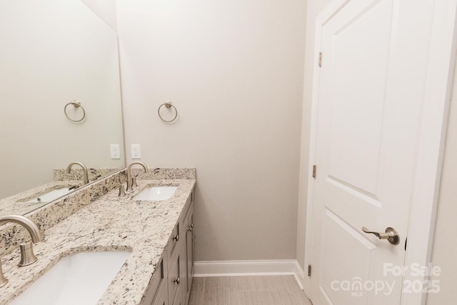 bathroom with double vanity, a sink, and baseboards