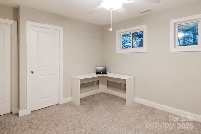 unfurnished office with light carpet, ceiling fan, visible vents, and baseboards