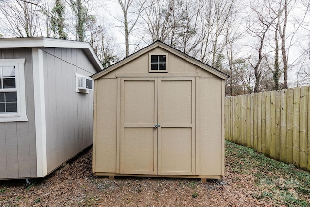 view of shed featuring a wall unit AC and fence