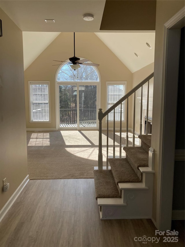 entrance foyer with lofted ceiling, wood finished floors, a ceiling fan, baseboards, and stairway