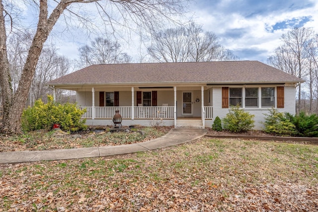 ranch-style home with roof with shingles, covered porch, and brick siding