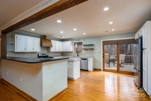 kitchen with open shelves, custom range hood, a peninsula, and appliances with stainless steel finishes