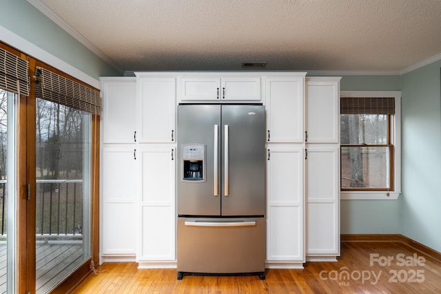 kitchen featuring stainless steel fridge, white cabinets, light wood-style flooring, and crown molding