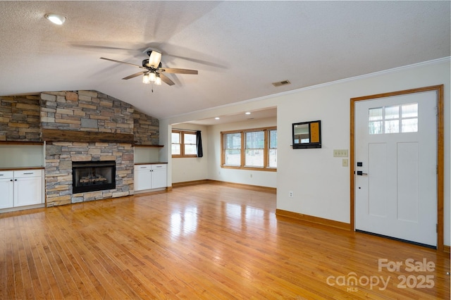 unfurnished living room with visible vents, ceiling fan, vaulted ceiling, light wood-style flooring, and a textured ceiling