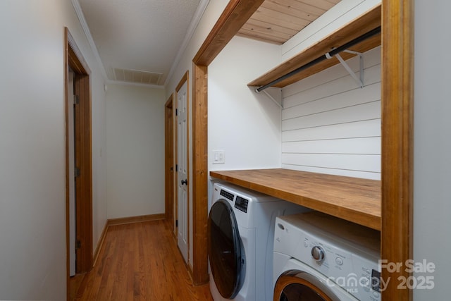 clothes washing area featuring wood finished floors, baseboards, visible vents, washing machine and clothes dryer, and laundry area