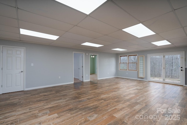 spare room with a drop ceiling, baseboards, and wood finished floors