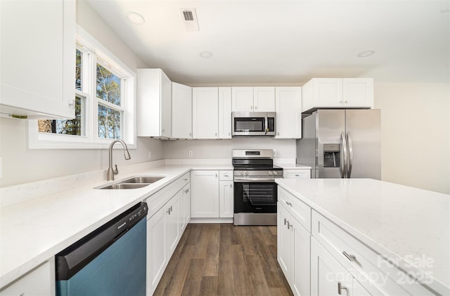 kitchen with dark wood-style floors, recessed lighting, appliances with stainless steel finishes, white cabinetry, and a sink