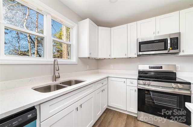 kitchen featuring light countertops, appliances with stainless steel finishes, a sink, and white cabinets