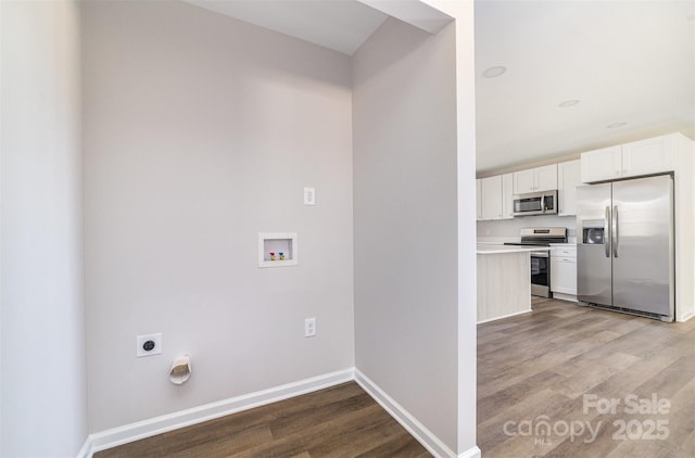 laundry area with laundry area, wood finished floors, and baseboards