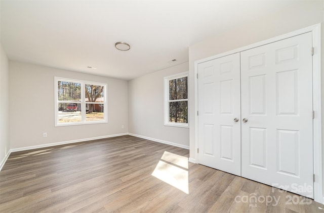 unfurnished bedroom with a closet, baseboards, and wood finished floors