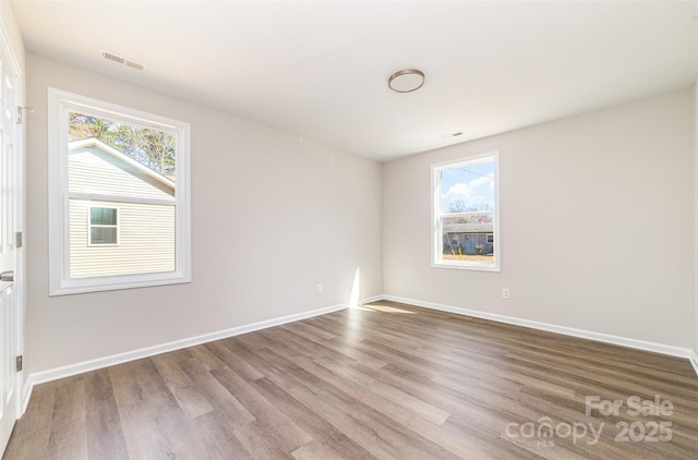 empty room with visible vents, baseboards, and wood finished floors