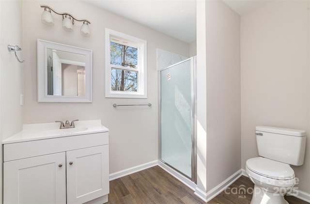 bathroom featuring toilet, a stall shower, baseboards, and wood finished floors