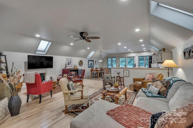 living room featuring a skylight, lofted ceiling, ceiling fan, light wood finished floors, and recessed lighting