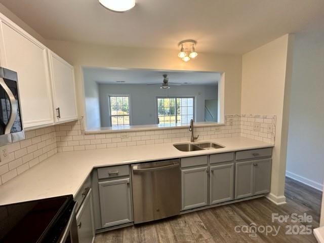 kitchen with decorative backsplash, dark wood-style flooring, gray cabinets, stainless steel appliances, and a sink