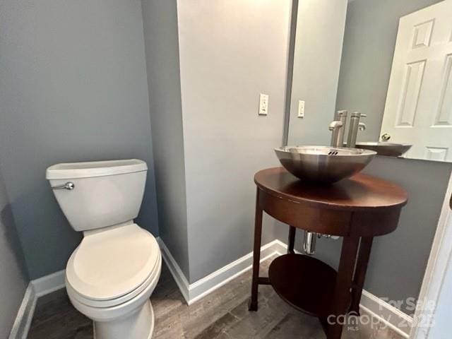 bathroom featuring toilet, baseboards, and wood finished floors