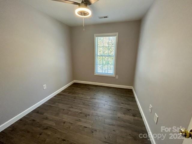 spare room with dark wood-style floors, baseboards, visible vents, and a ceiling fan