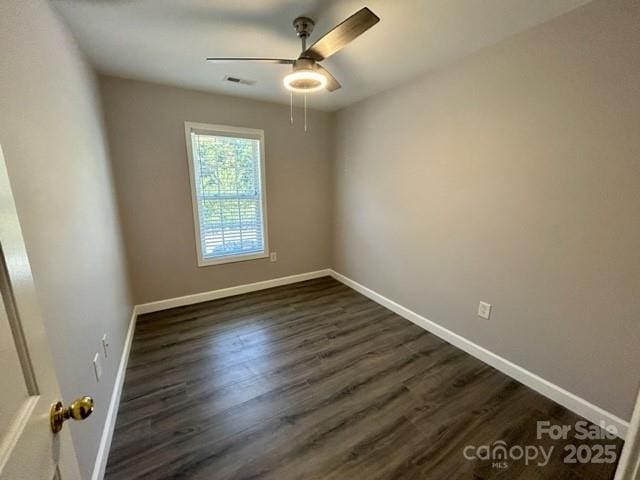 empty room with dark wood-type flooring, visible vents, ceiling fan, and baseboards