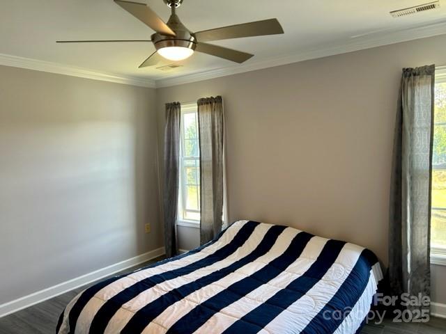 bedroom with baseboards, multiple windows, visible vents, and crown molding