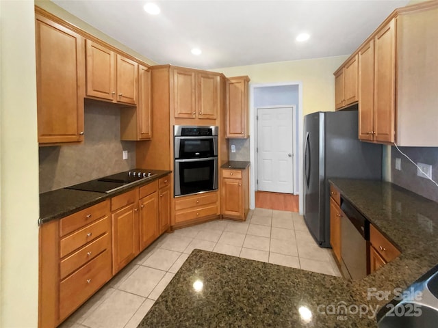 kitchen featuring stainless steel appliances, dark stone counters, recessed lighting, and light tile patterned floors