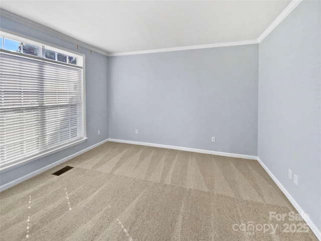 empty room with carpet floors, baseboards, visible vents, and ornamental molding