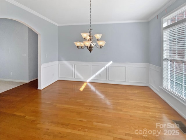 unfurnished dining area with a chandelier, arched walkways, visible vents, and light wood-style floors