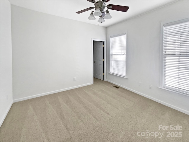 carpeted empty room with baseboards, visible vents, and ceiling fan