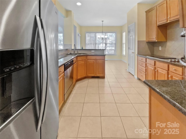 kitchen with light tile patterned floors, a peninsula, stainless steel appliances, a chandelier, and a sink