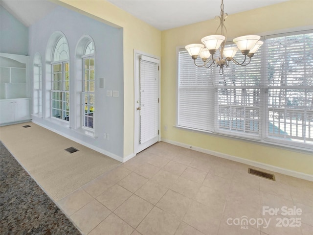 unfurnished dining area with tile patterned flooring, visible vents, a notable chandelier, and baseboards