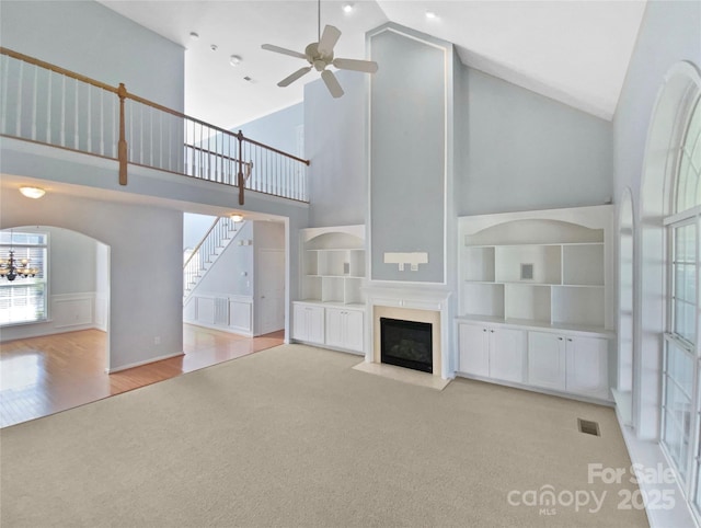 unfurnished living room featuring carpet, a fireplace with flush hearth, visible vents, and a wealth of natural light