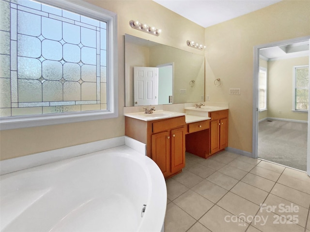 full bath with tile patterned flooring, vanity, a bath, and baseboards