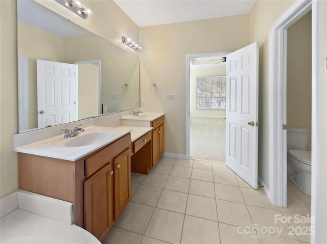 full bathroom featuring ceiling fan, two vanities, a sink, and toilet