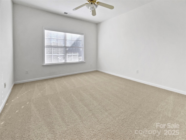 carpeted spare room with visible vents, a ceiling fan, and baseboards