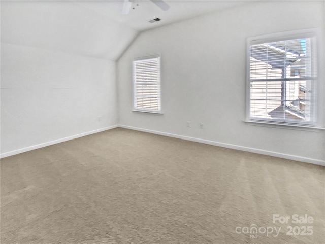 interior space with carpet floors, lofted ceiling, visible vents, a ceiling fan, and baseboards