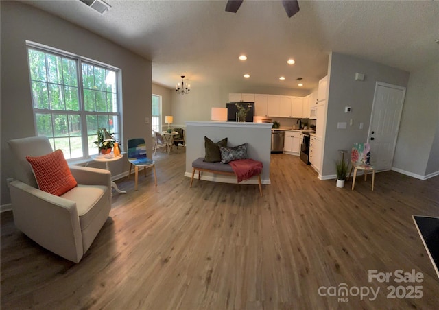 living room with recessed lighting, visible vents, light wood-type flooring, baseboards, and ceiling fan with notable chandelier