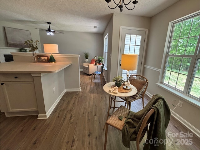 dining area with a textured ceiling, visible vents, dark wood-style floors, baseboards, and ceiling fan with notable chandelier