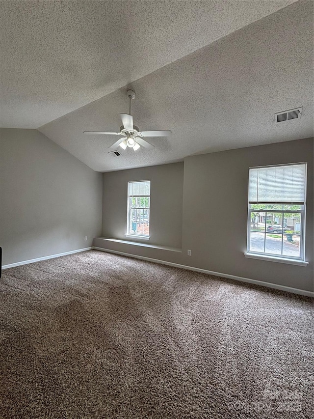 carpeted spare room with vaulted ceiling, visible vents, baseboards, and ceiling fan
