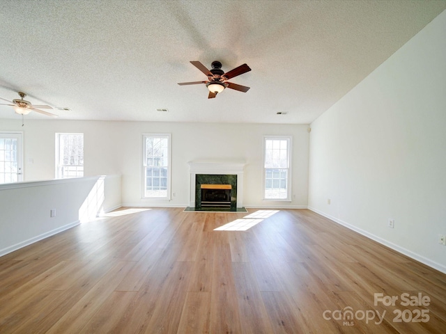 unfurnished living room featuring light wood-style floors, a wealth of natural light, and a high end fireplace