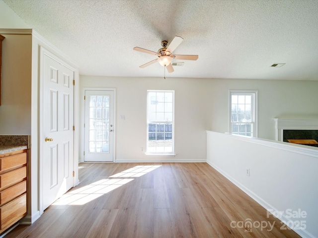 interior space featuring a textured ceiling, a fireplace, visible vents, and wood finished floors