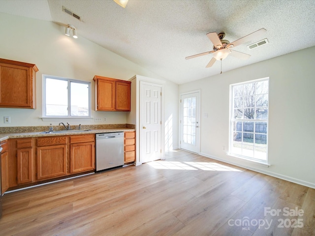 kitchen with brown cabinets, lofted ceiling, visible vents, stainless steel dishwasher, and light wood-style floors