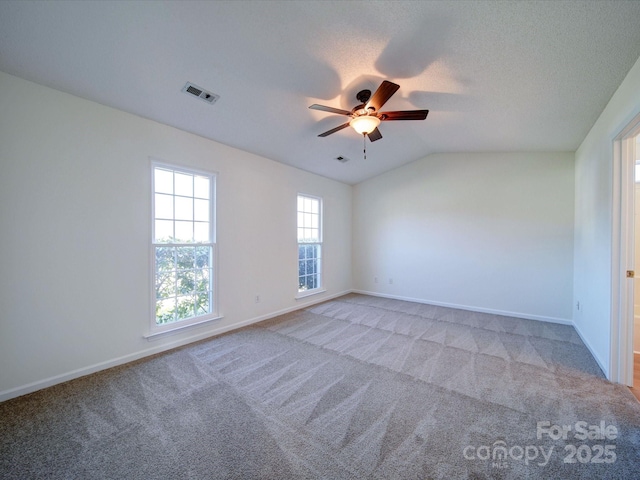 unfurnished room with light colored carpet, visible vents, vaulted ceiling, and baseboards